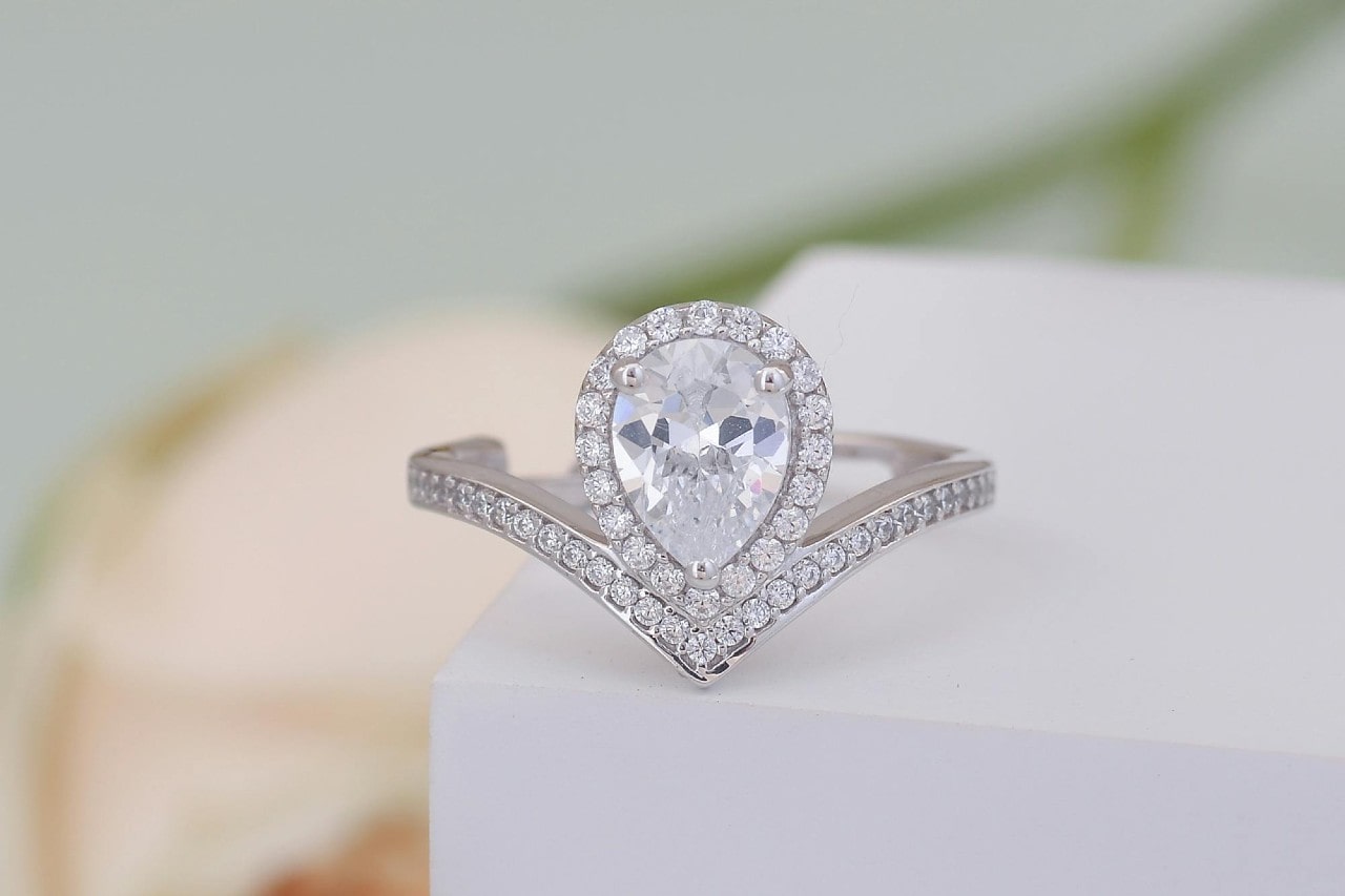 a unique white gold engagement ring featuring a pear shape center stone and curved band