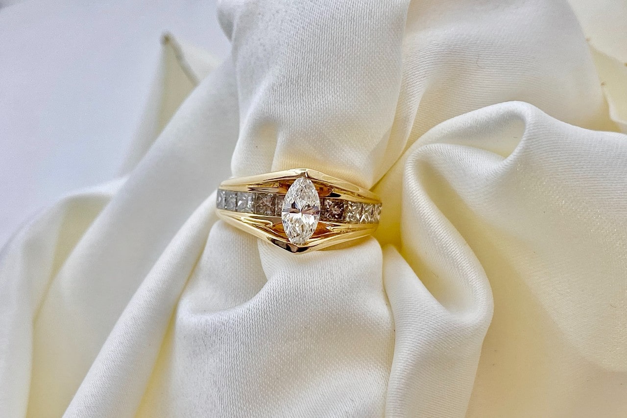 an engagement ring with a thick gold band and a marquise cut center stone
