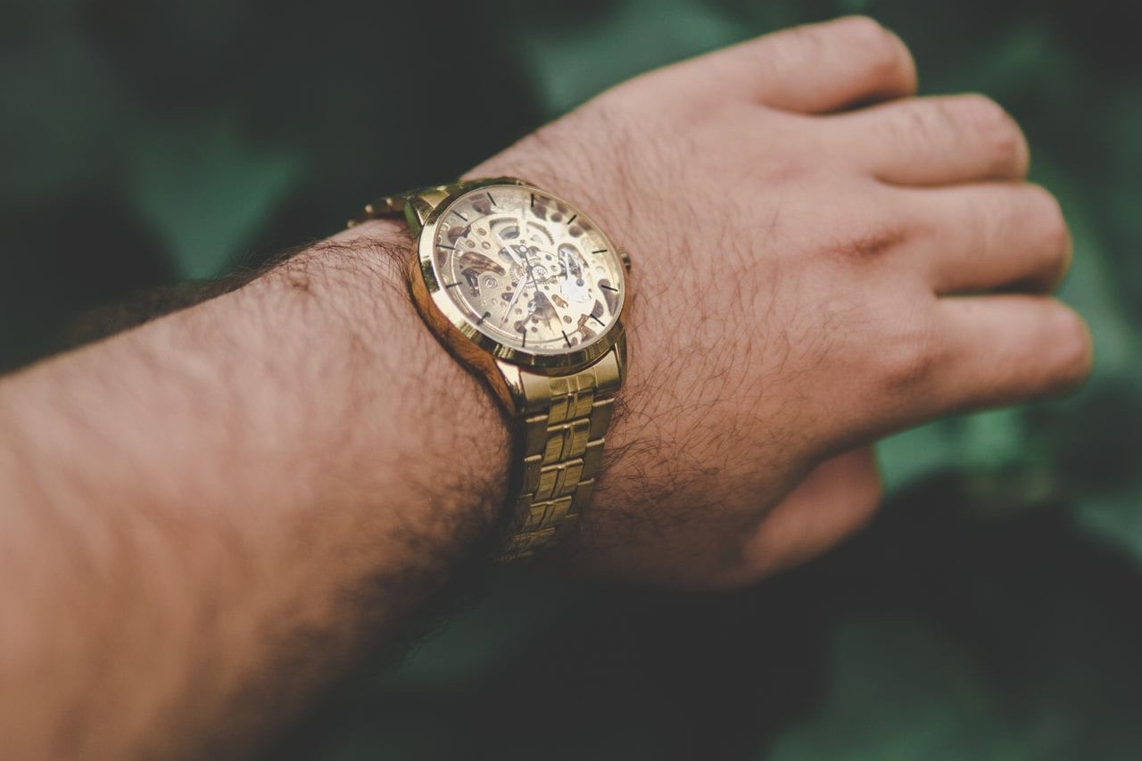 An attractive yellow gold watch with a skeletal dial on a man’s wrist