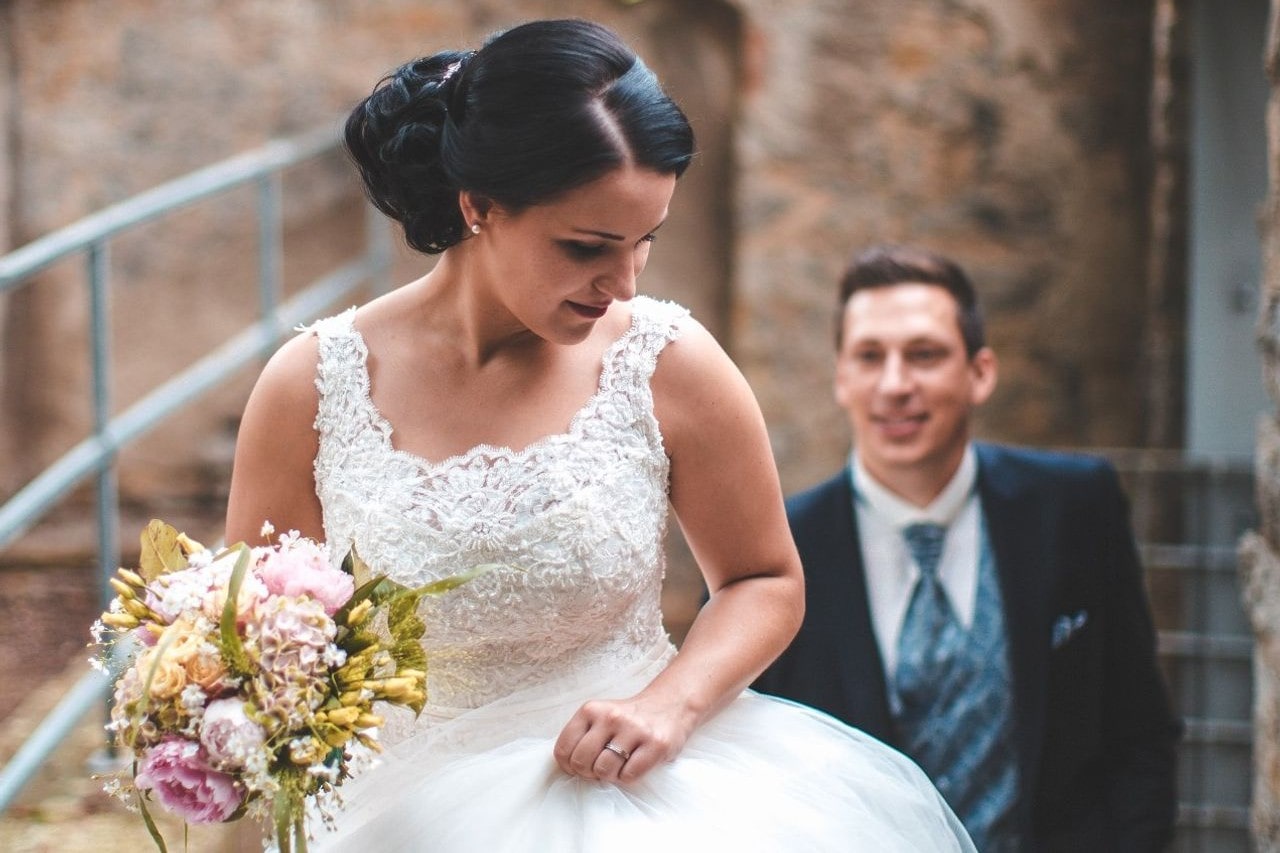 A bride facing away from her groom with the groom smiling in the background