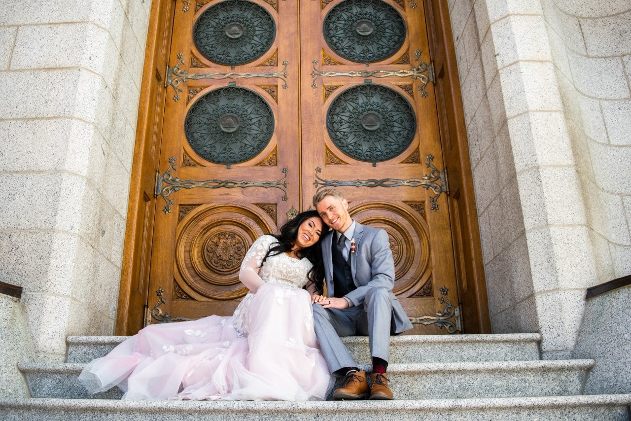 Bride and groom sitting together on the steps of and old church