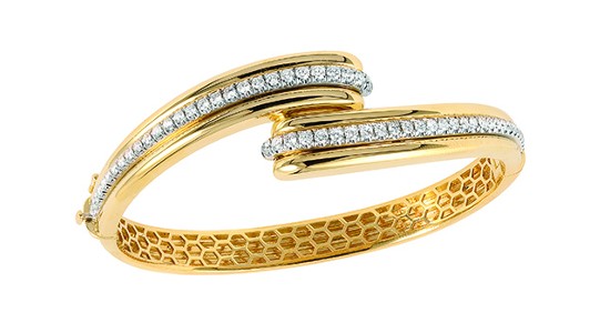 An asymmetrical gold bangle with diamond details and a honeycomb pattern along the inside