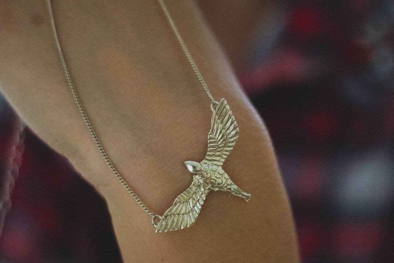 Close-up image of a gold chain necklace featuring a large, golden eagle motif