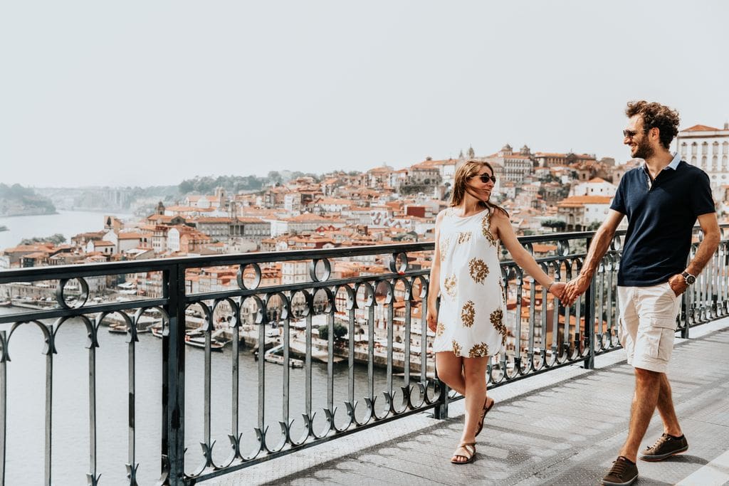 A woman and her fiance stroll over a bridge in a Roman city