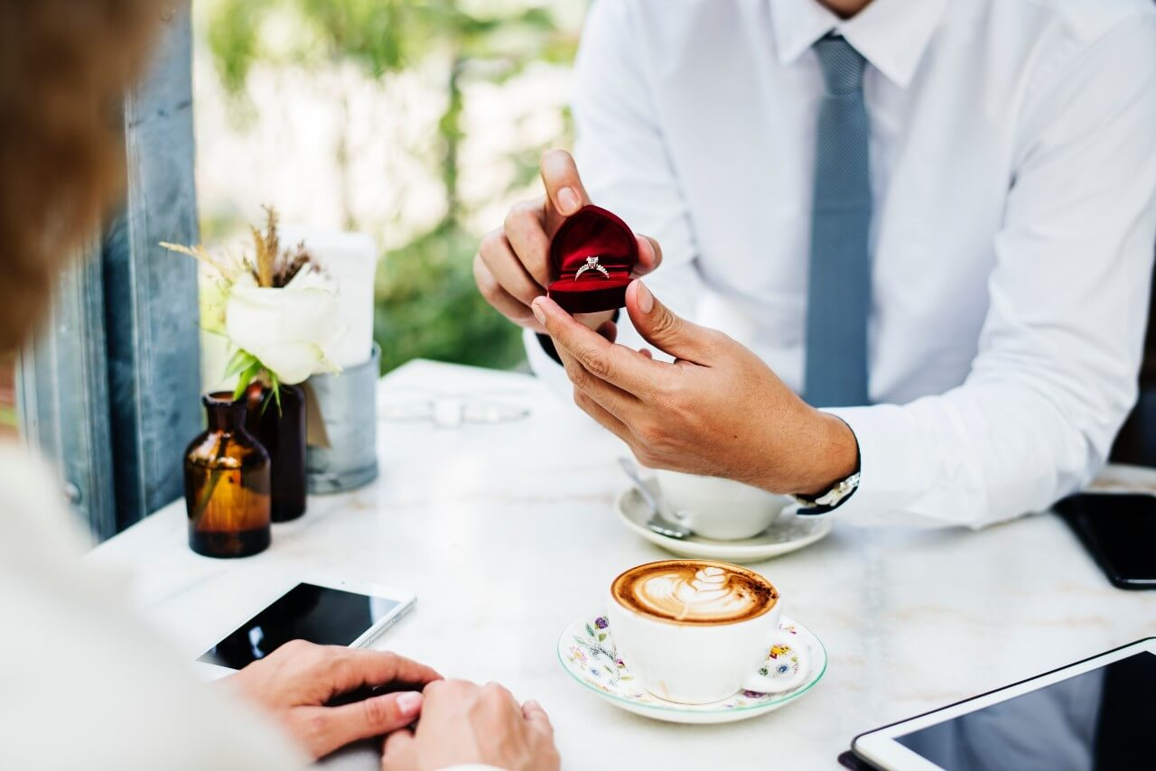 A man pops the question to his sweetheart at an outdoor cafe