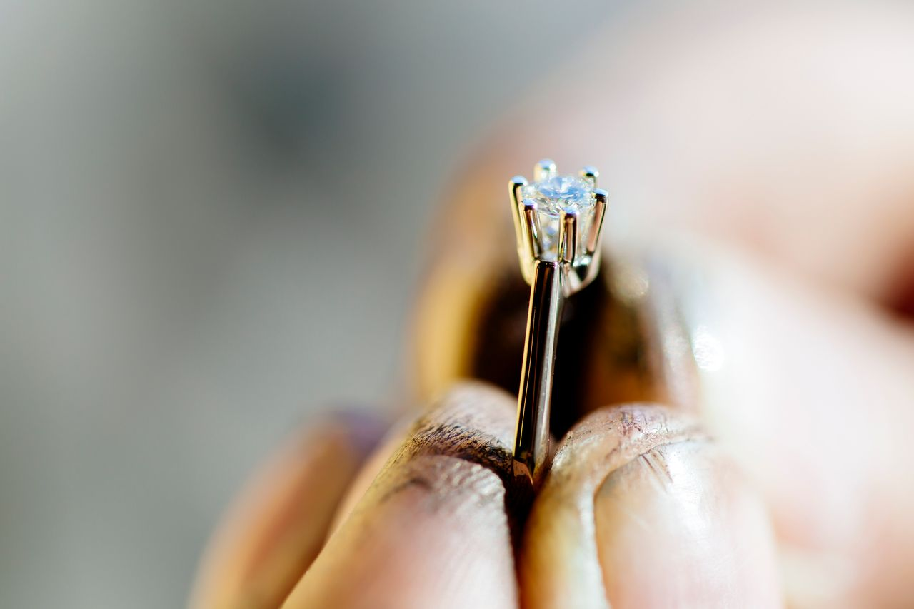 A jeweler shows off his work after polishing a solitaire engagement ring