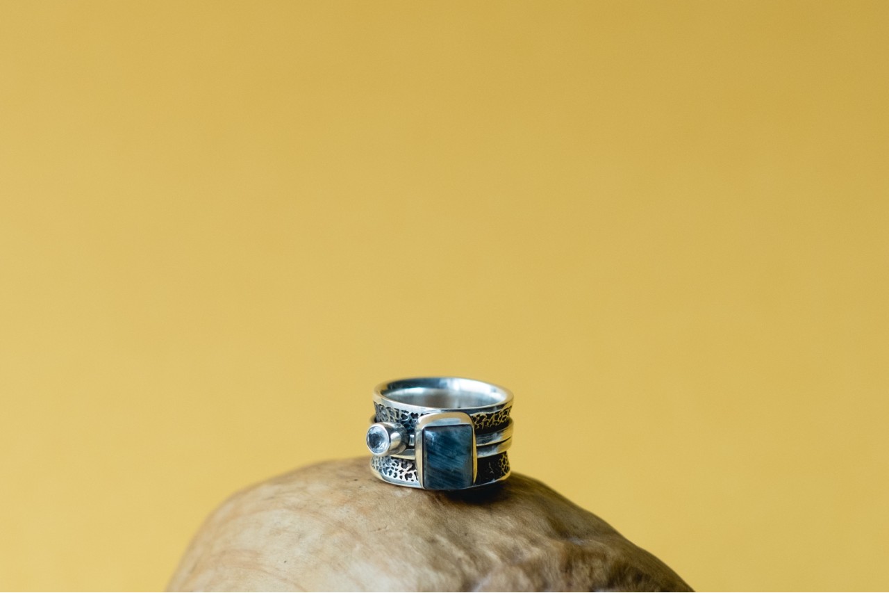 Silver ring with a large blue gemstone against a yellow background