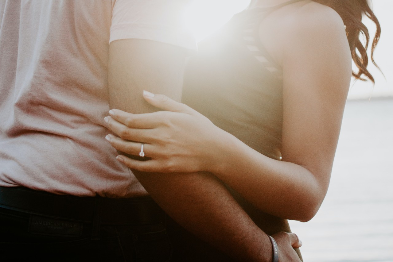 Man and woman embracing in front of a body of water