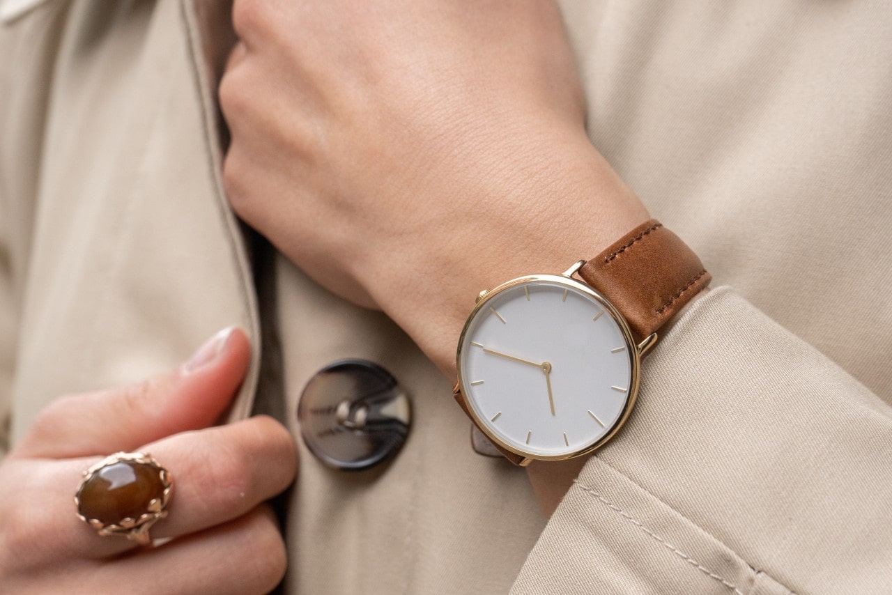 Close up image of a person wearing a minimalist watch, a nice coat, and a large cocktail ring