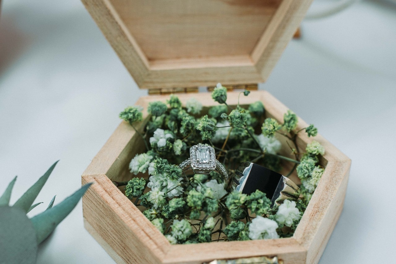 Diamond engagement ring sitting in a box with flowers