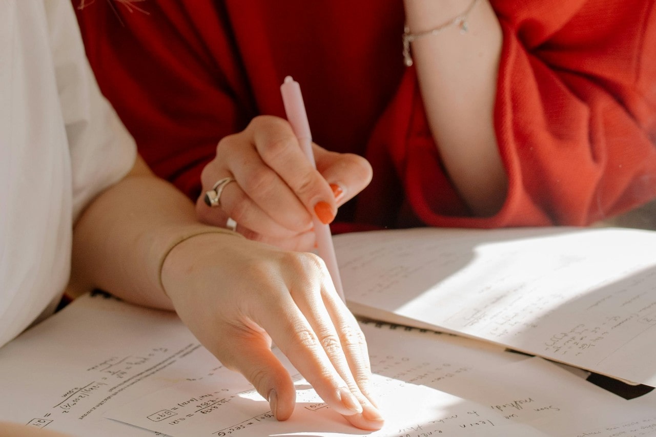 Two women pouring over papers and wearing pieces of fine jewelry.