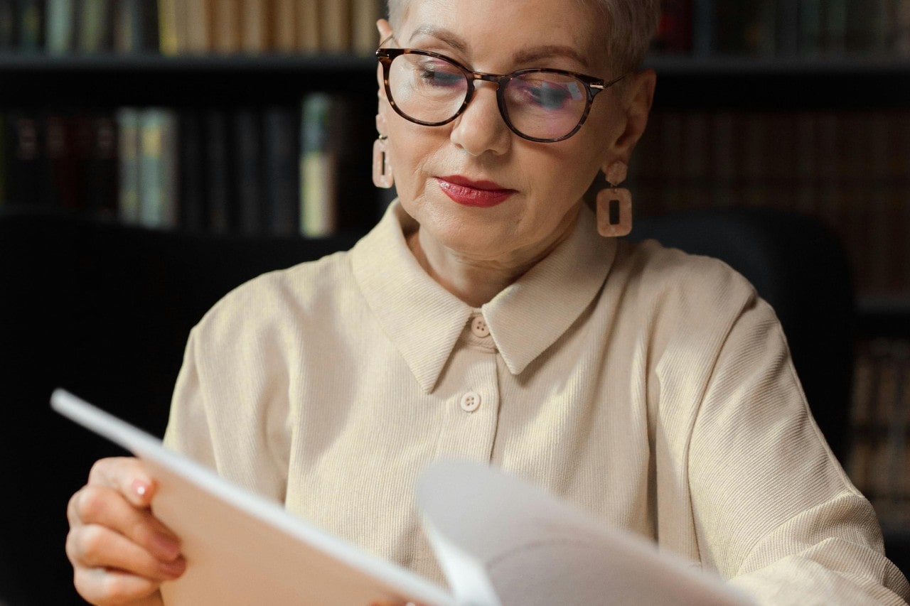 A woman looking through papers in a library and wearing large earrings.