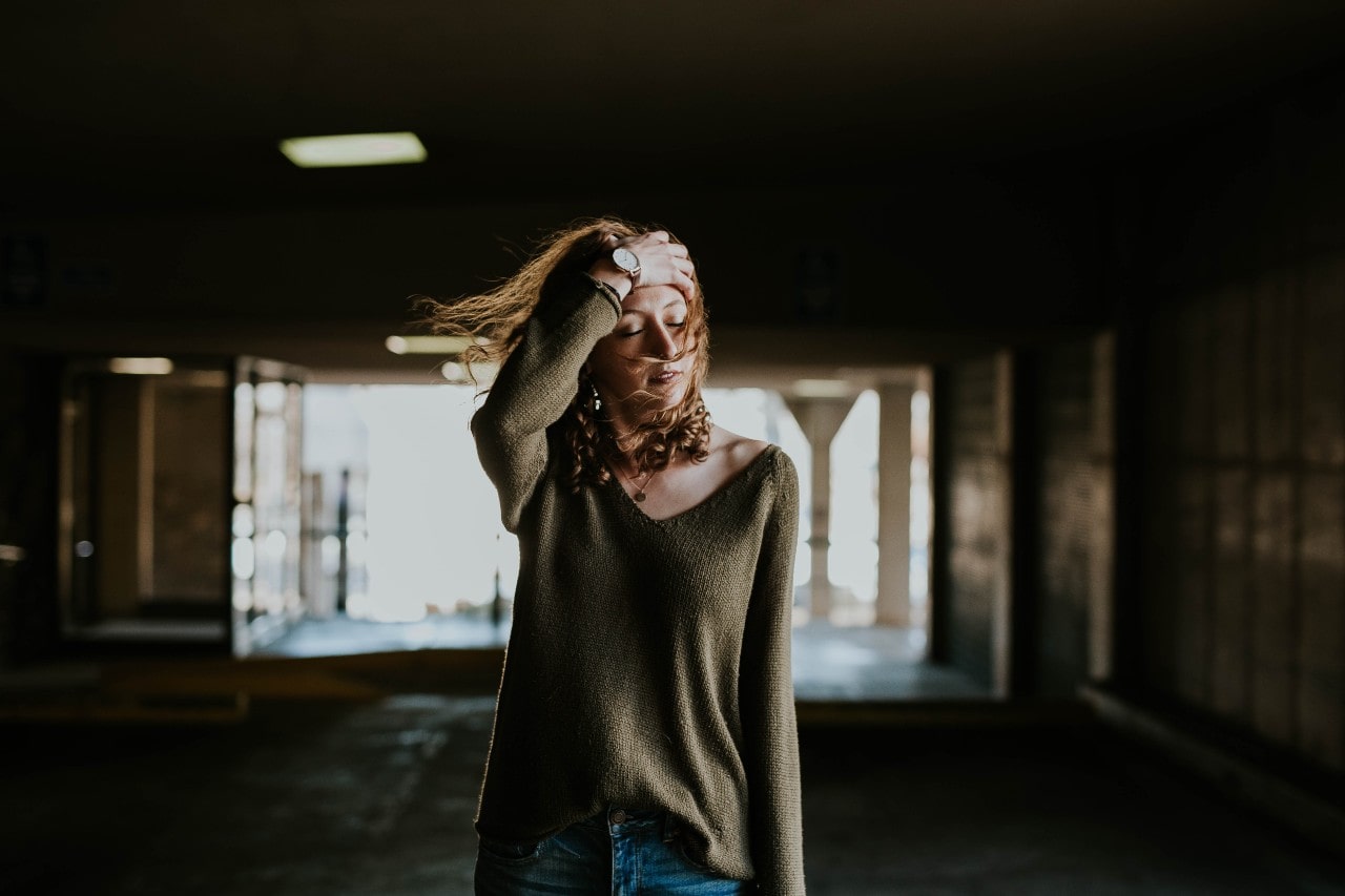 A woman walks through a tunnel with the wind blowing on her.