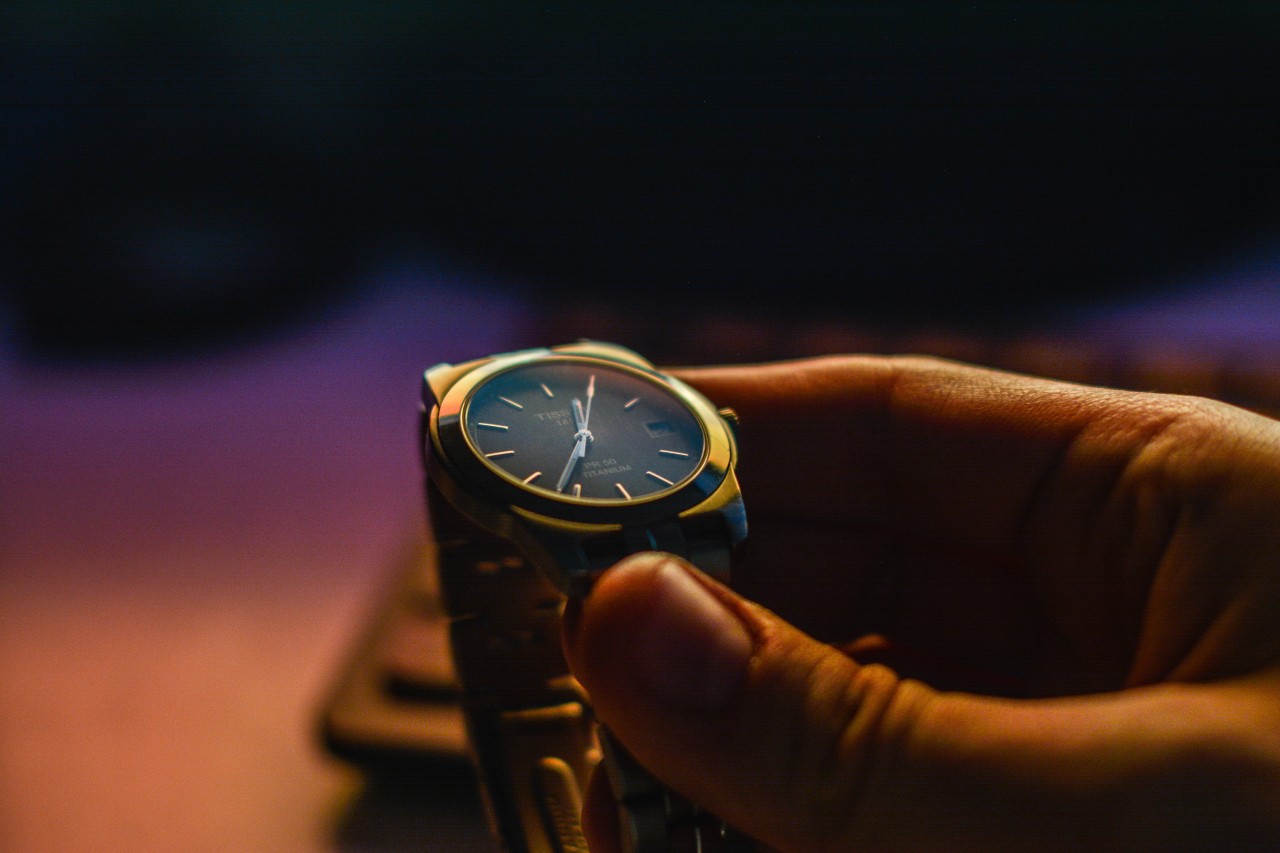 A man holding an elegant wristwatch under dramatic lighting.
