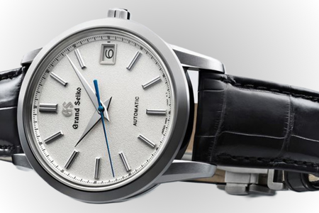 A close-up image of a Grand Seiko watch with a silver-toned dial and bezel.