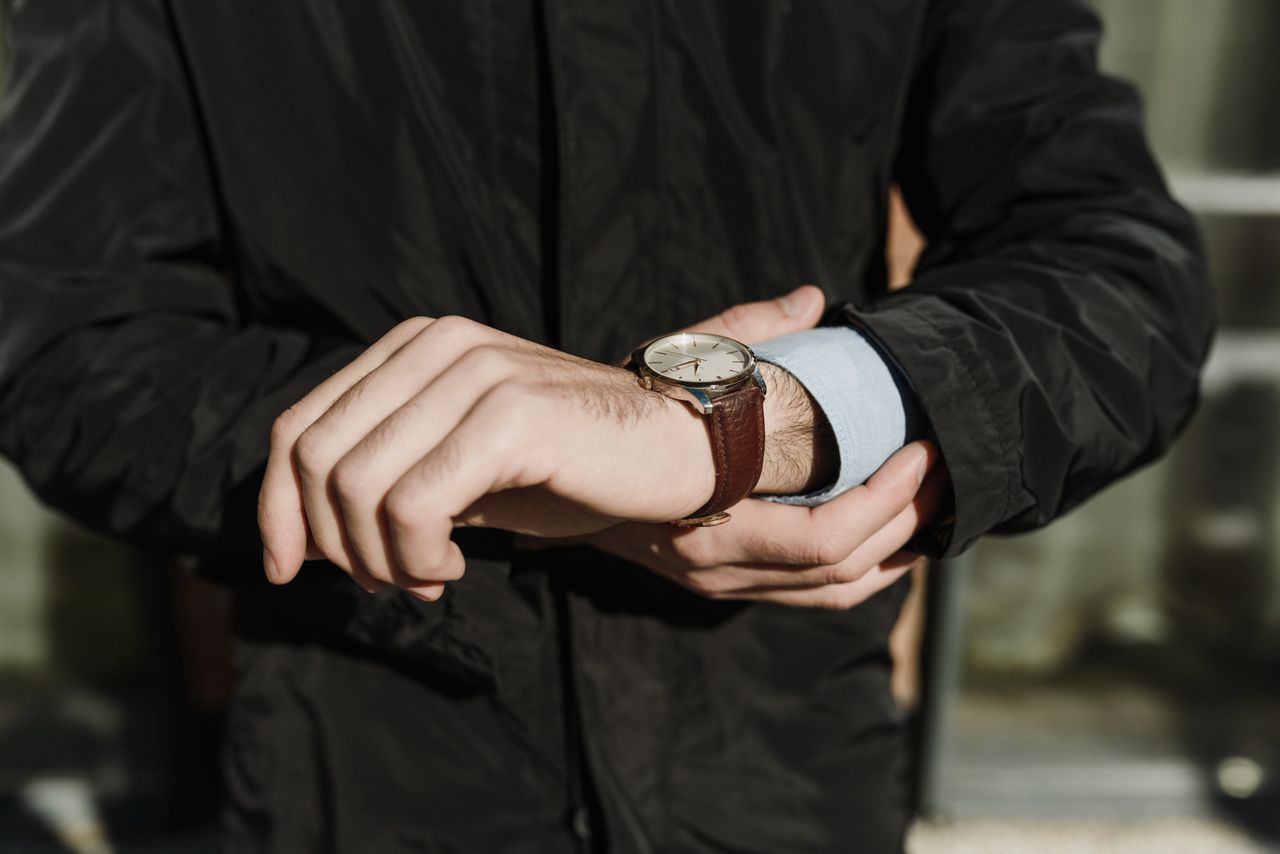 man in coat looking at automatic watch