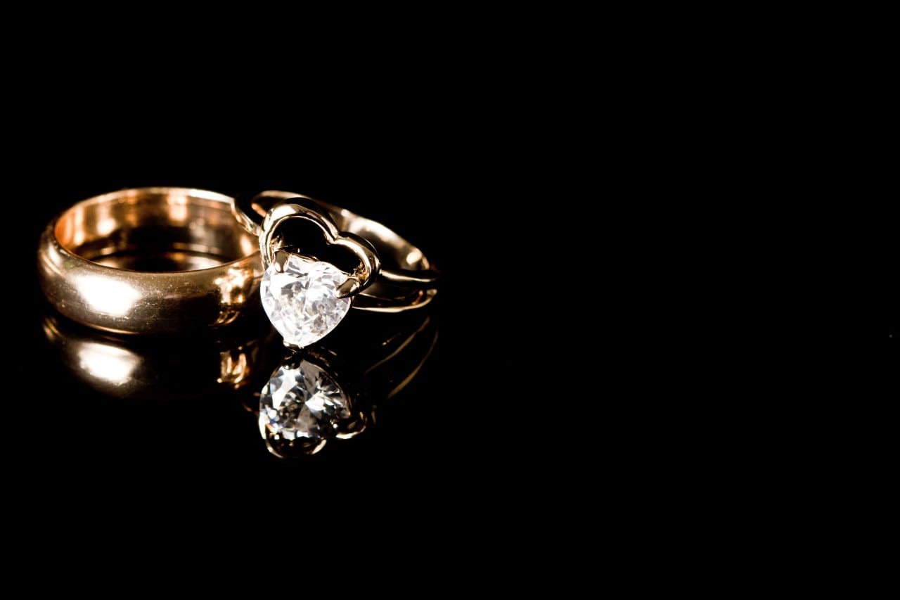 A gold heart-shaped diamond engagement ring with a gold wedding band.